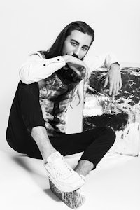 a man with long hair sitting on top of a piece of metal