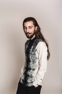 a man with long hair and a tie dye shirt