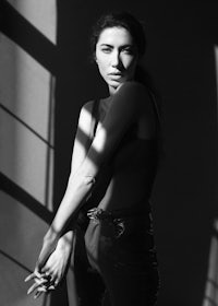 a black and white photo of a woman posing in front of a window