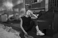 a black and white photo of a woman sitting on the edge of a building
