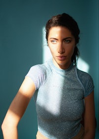 a woman is posing in front of a blue wall