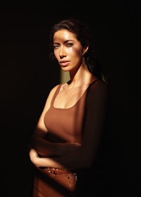 a woman in a brown top posing in front of a window