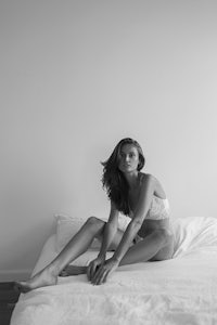 a woman sitting on a white bed