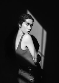 a black and white photo of a woman leaning against a wall