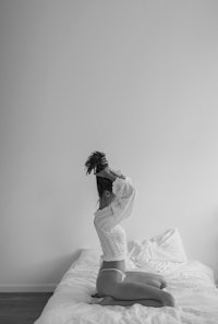 a black and white photo of a woman sitting on a bed