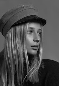 a black and white photo of a woman wearing a hat