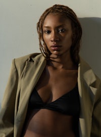 a woman in a black bikini and a tan jacket